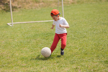 Little boy kicking ball in the park. playing soccer (football) in the park. Sports for exercise and activity.