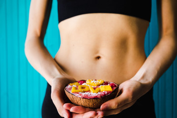 Concept of diet, proper nutrition and health. A girl holding a smoothie bowl on wooden turquoise background.