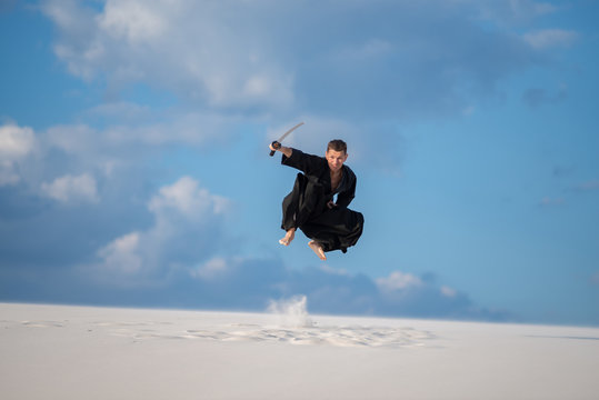 Expressive man jumps with a Japanese sword, katana
