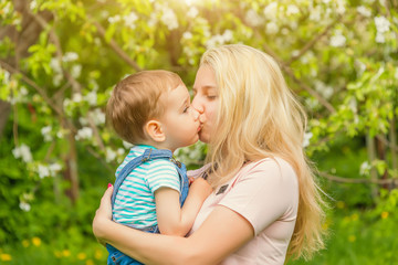 mom hugs and kisses baby in the Park