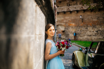 Obraz premium Beautiful young bride posing in a wedding blue dress in old street, 