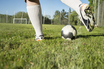 Im Sommer spielt ein Mann ganz alleine mit einem Fußball. Er steht an der Außenlinie und schießt...