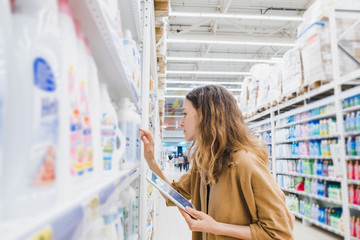 Young business woman with a tablet reads the composition of the goods in a supermarket