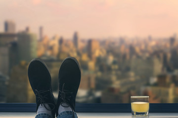 A male feet in the shoes on the balcony on the background Manhattan. New York City
