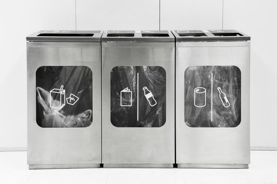 silver metal bins on white background in a public place for different garbage (glass, can, plastic, paper and food waste), nature conservative concept