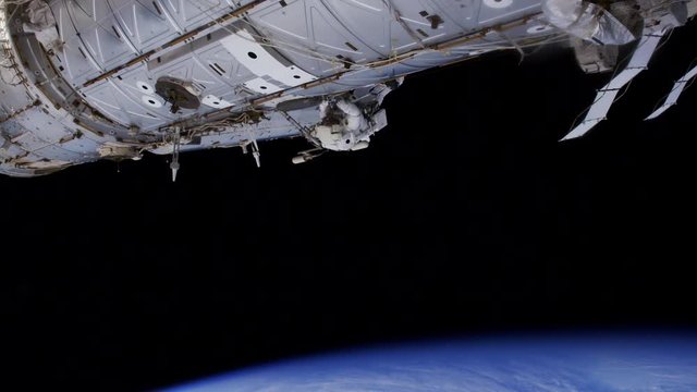 Low angle, astronauts climbs on exterior of International Space Station