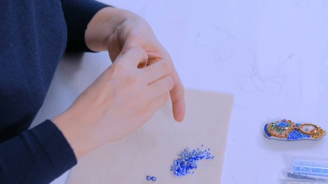 Professional jewelry designer making handmade eardrop with beads in studio, workshop. Fashion, creativity and handmade concept