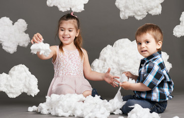 child playing with clouds, shot in the studio on a gray background