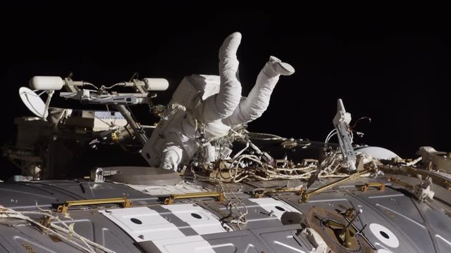 Low angle, astronaut climbs on International Space Station