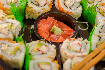 Close up of selective focus of large set of delicious japanese sushi rolls on a black plastic plate