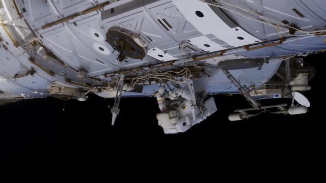 Low angle, astronaut hanging on outside of International Space Station