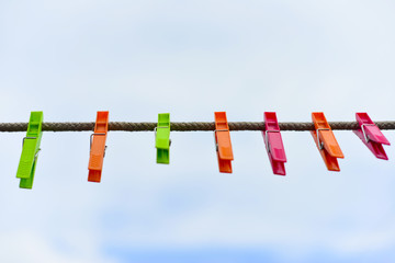 Color clothespins hang on the clothesline. laundry hook, colorful, pegs, rope ,outside, sun ,green, summer decorations, village, blue, sky , yellow ,red ,pins ,pink ,over