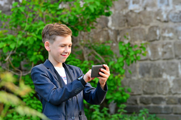 A boy with a camera is writing a message on a smartphone, on the street