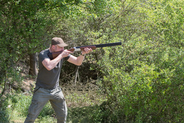 Hunter in forest during hunting season aiming before shoot