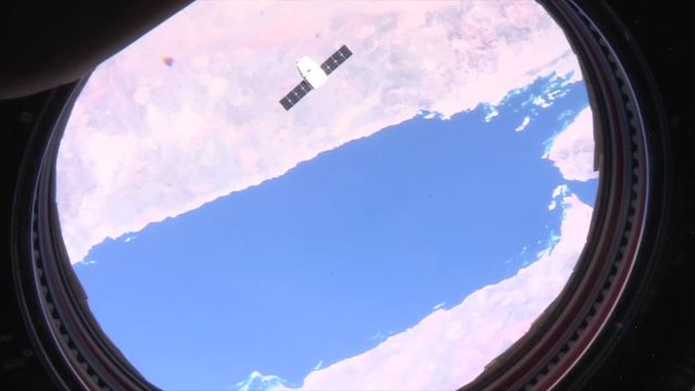 High angle, satellite flies underneath International Space Station