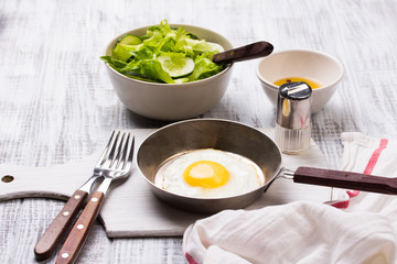 Fried eggs in a frying pan with tomatoes and vegetable salad for breakfast