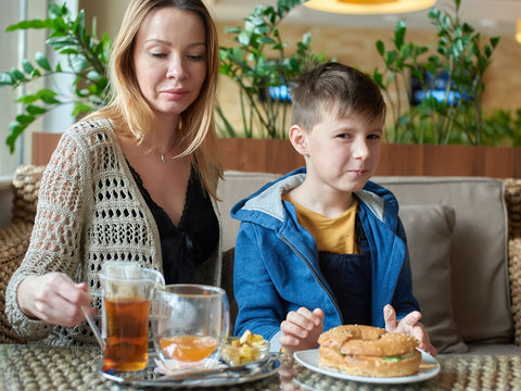 Caucasian Mom And Son Enjoying Their Meal At A Restaurant.