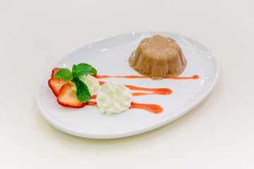 Caramel Pudding served with strawbery sauce, whip cream, sliced fresh strawberry and mint.