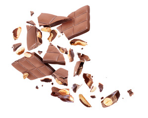 Chocolate bar with nuts broken into pieces in the air on a white background