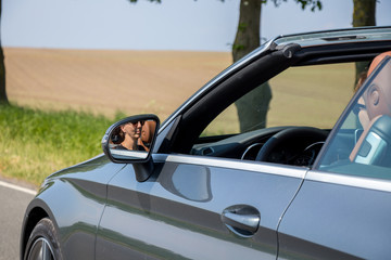 woman in sunglasses driving a luxurious convertible car