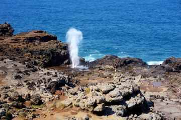 Tourists admiring the Nakalele blowhole on the Maui coastline. A jet of water and air is violently forced out through the hole in the rocks, Hawaii