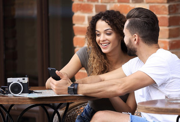 Portrait of a young  couple sitting down at a cafe terrace