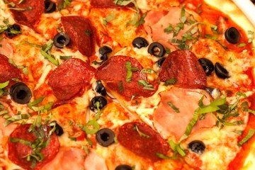 Homemade salami pizza with ham and olives. Close-up view of fresh pizza.