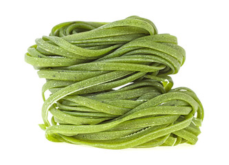 Two nests of green tagliatelle isolated on white background