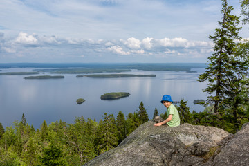 The boy is sitting on the rock in Koli National Park, Finland