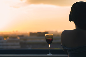 Silhouette of woman hand with glass of red wine on sunset