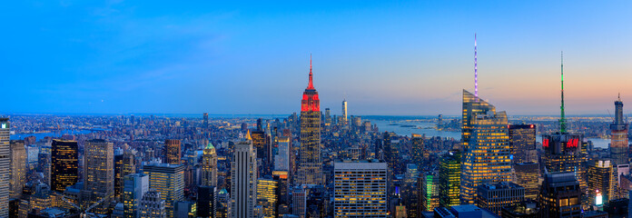 Manhattan downtown skyline with illuminated Empire State Building and skyscrapers at sunset