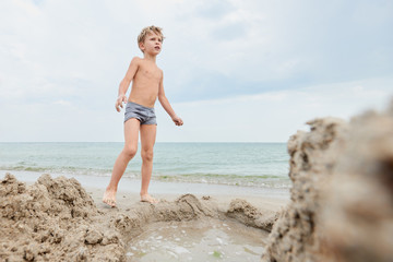 Portrait of young blond boy having fun on the seashore