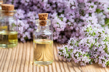 Obraz na płótnie Canvas A transparent bottle of essential oil with fresh blooming thyme