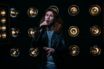 men singer with long hair, with microphone on the stage