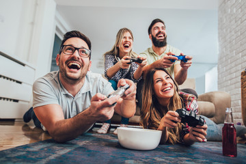 Group of friends play video games together at home, having fun. - obrazy, fototapety, plakaty