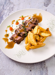 Top view grilled beef steak and fried potatoes on background, restaurant menu concept. Beautiful juicy meat on plate.
