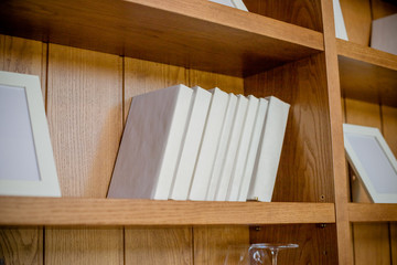 shelf with books. White Books, knowledge, education concept. Interior details.Selective focus.Bookshelf.stack of books on the wooden shelves near the wall