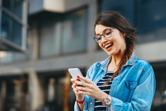 Young Woman Reading A Message On The Phone In The City