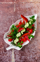 Top view simple salad - sliced red tomatoes and green cucumbers with greenery on white plate, background, restaurant menu concept. Vegetarian, summer food, healthy lifestyle.