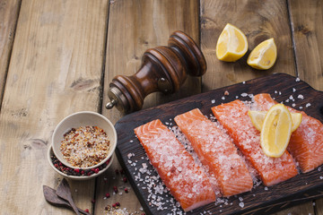 Fillet of salmon on the board, sea salt and spices. Preparation of a delicious and healthy dinner. Fitness food. Wooden background. place for text. Horizontal photo