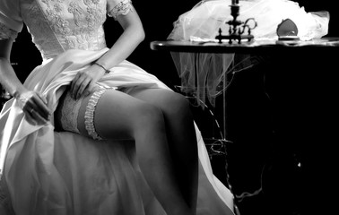 Wedding night preparing garter. Bride undressing and put veil on table. Candle illuminates house. Girl choosing stocking before wedding. Memories of mother about wedding. Black and white old photo.
