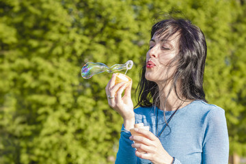 A young woman is having fun, blowing bubbles.