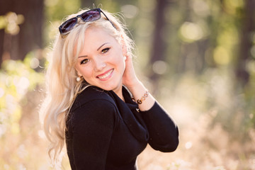 A young, blond and smiling woman portrait on a sunny autumn day.