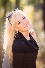 Naklejka premium A young, blond and smiling woman portrait on a sunny autumn day.