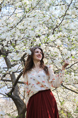 Fototapeta na wymiar Young girl in beautiful magnolias tree garden