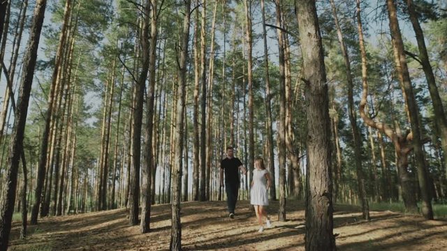 Happy couple hugging and kissing at the edge of the cliff. Young man and woman running through the forest.