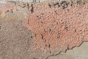 surface of the old wall with exfoliating and falling off paint as a background, pink texture