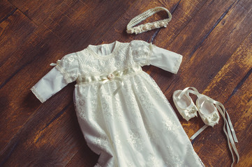 christening baby dress and shoes. Close-up of a cute newborn. small shoes and a dress on a background of wood. Concept childhood education and fashion