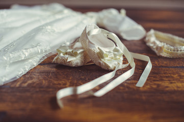 christening baby dress and shoes. Close-up of a cute newborn. small shoes and a dress on a background of wood. Concept childhood education and fashion