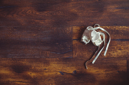 Close-up of cute baby shoes on a wooden background. Stylish children's shoes. White children's shoes on a dark background place for text. Concept childhood education and fashion